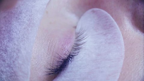 Extreme close up woman eye. Eyelash extension procedure. Young woman in a beauty salon