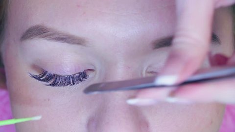 Time lapse. Close up. The master in the beauty salon removes the old eyelashes, preparing the patient for the process of eyelash extension