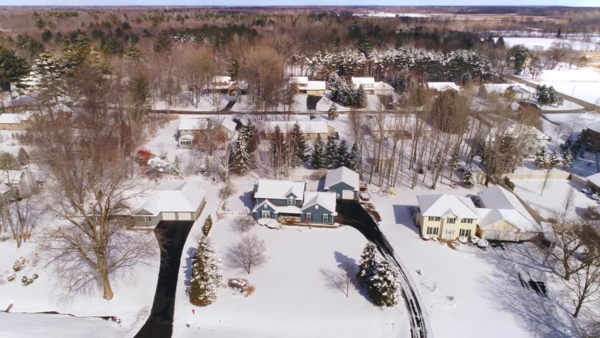 Beautiful Northern Wisconsin homes with pine trees under fresh snow, aerial view.
