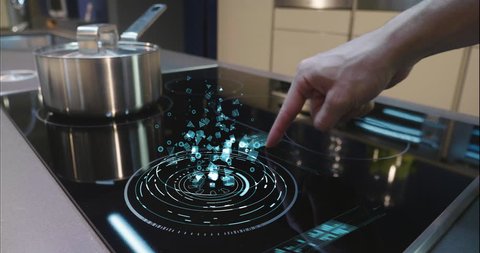 Close up of a man who cooks in his own home on a stove of the latest technology and regulates power and intensity thanks to holography. Concept of: future, technology, kitchen, augmented reality.