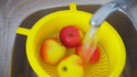 fresh ripe apples in a colander are washed in the kitchen sink under a stream of water.1920X1080 FullHD video