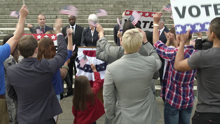 A politician giving a speech in front of an applauding crowd