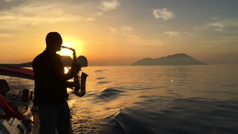 Man playing saxophone on sunset background
