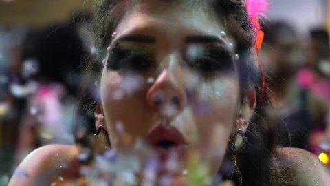 Girl blowing colorful confetti at Salvador Carnaval, Brazil