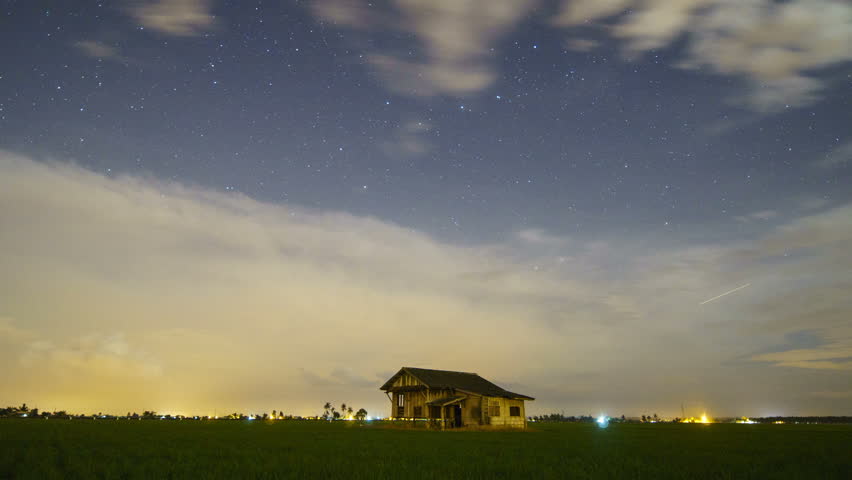 Night star trails time lapse of old abandoned house in the middle of paddy field at Kampung Sungai Sireh, Tanjung Karang, Selamgor, Malaysia.