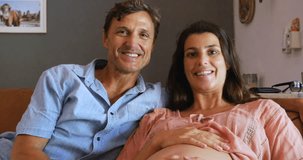 Beautiful pregnant couple with a new baby on the way saying goodbye on a video conference call