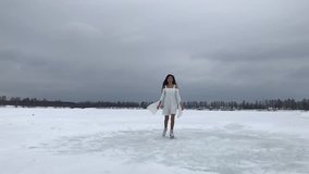 Young woman in white dress and skates at winter (part of video in slow motion)