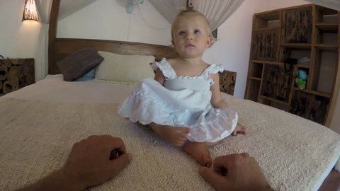 Man tickling and playing with a young toddler one year old baby girls feet while she laughs - POV