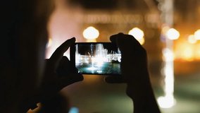 Tourist recording video with smartphone, Musical Fountains image on screen