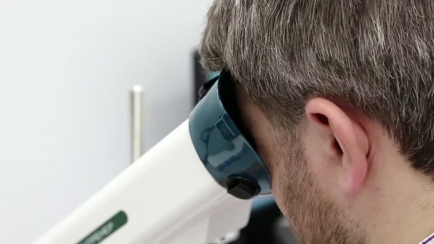 Man looks in apparatus for the treatment of spasm of accommodation, amblyopia and binocular vision disorders. Patient in ophthalmology clinic Royalty-Free Stock Footage #1008579721