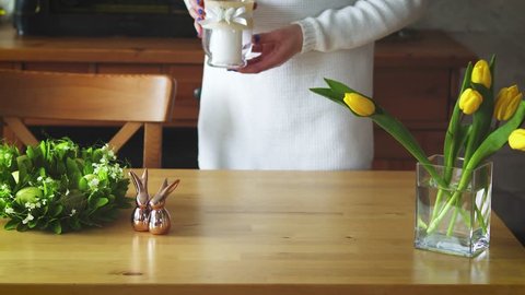 woman decorates a wooden table with Easter decorations