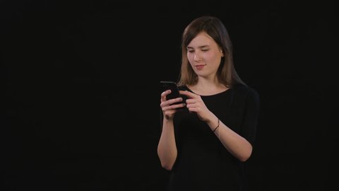 A beautiful young lady using a phone against a black background. Medium Shot
