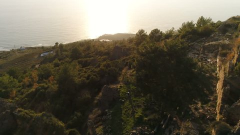 Beautiful copter view of the Syedra Castle ruins on the green rocky Taurus Mountains during the sunset. Antalya Province in Turkey. Slow motion, 4k.