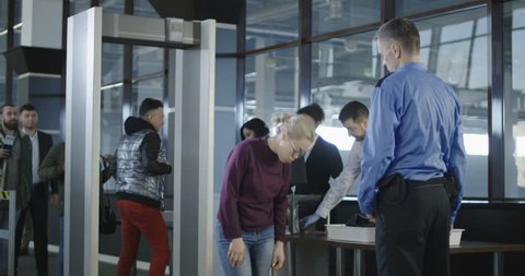 People going through procedure of physical inspection and luggage scanning in airport. 4K shot on Red cinema camera.