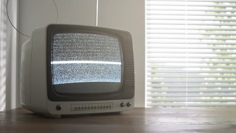 Vintage television on a table displaying static noise on the screen, retro revival and broadcasting concept