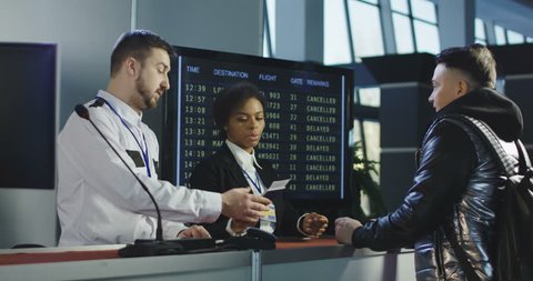 Man giving fingerprints with sensor when passing special control point in airport with employee watching at screen. 4K shot on Red cinema camera.