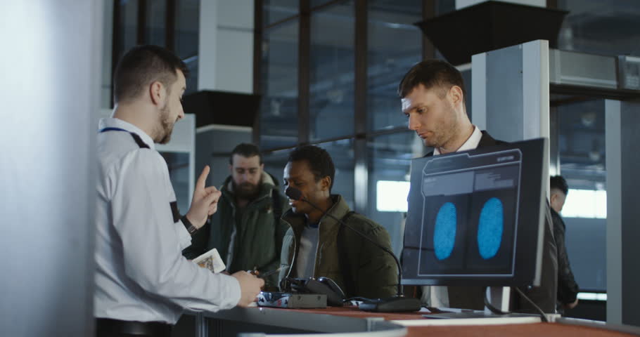 Security officer checking a male passenger thumb print and passport at an airport check-in counter with a view of the computer screen showing the scan being processed. Royalty-Free Stock Footage #1008584815