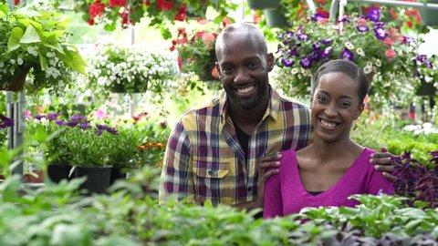 Young couple looking at camera while standing in a greenhouse
