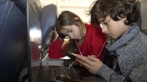 4k, close-up, children, passengers use the phone in an airplane against the porthole.