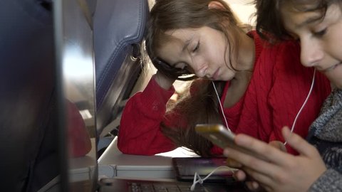 4k, close-up, children, passengers use the phone in an airplane against the porthole.