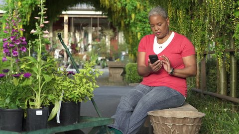 Senior woman using her smartphone in a garden