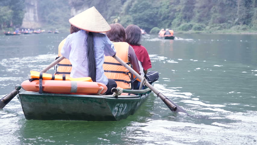 Tourist are traveling by sitting on the rowing boat in the river, Ninh Binh, Vietnam, slow motion.