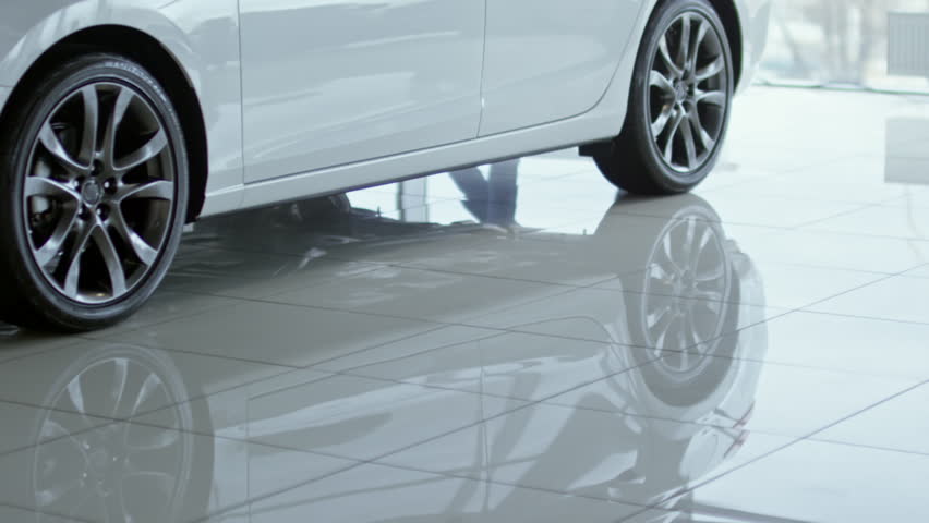 Tilt up of professional saleswoman in formal clothes showing new car to male client in suit