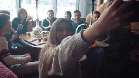 Young company is making selfie. Smoking a hookah and communicating in an oriental restaurant. Lebanon cuisine served in restaurant.
