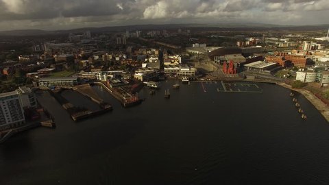Cardiff Aerial backward motion over Bay, city centre with docks and museum, Cardiff millennium stadium in distance.
