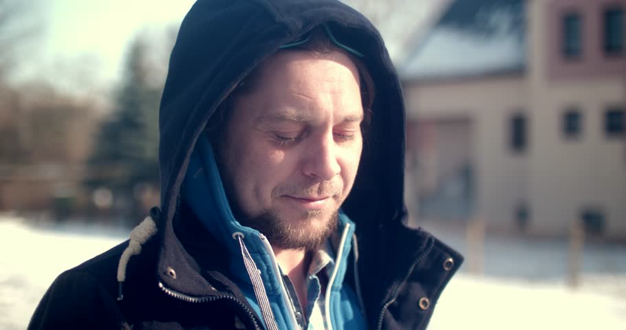 Serious bearded man smoking on a snowy street