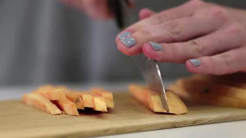 Slow Motion Medium Close Up Shot Of Woman Cutting A Sweet Potato Into Thin Slices/Sticks For Homemade Fries