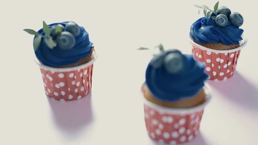 Three cupcakes with blue cream on a rectangular plate. Sequence - camera pan and focus pull
