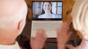 Top view of retired senior couple at home having video chat on laptop with their daughter. College student abroad talking to her parents via messenger app call