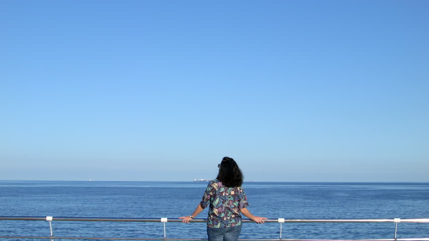 Woman standing on wooden pier looking into the distance. 4K wide frame