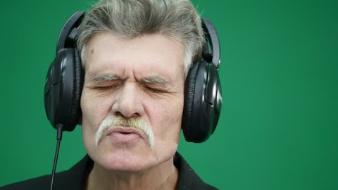The old man in headphones, listening to music, dancing, smiling, cheerful