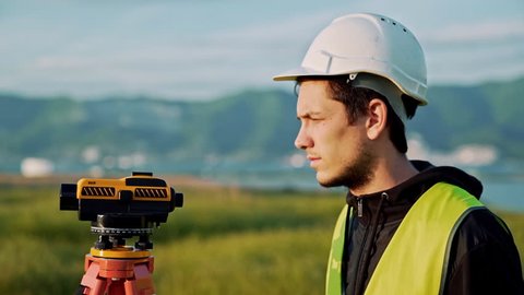 Surveyor engineer is measuring level on construction site. Geodesist ensure precise measurements before undertaking large construction projects. Concept of landscape design