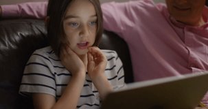 4K Zoom in to close up on face of little girl, engrossed in watching computer screen