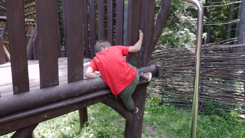 Curious active boy climbing in adventure park on a summer sunny day