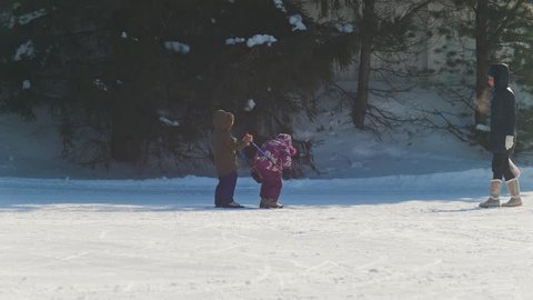 KAZAN, RUSSIA - March, 2018: two children playing in winter, a boy skiing, a girl running