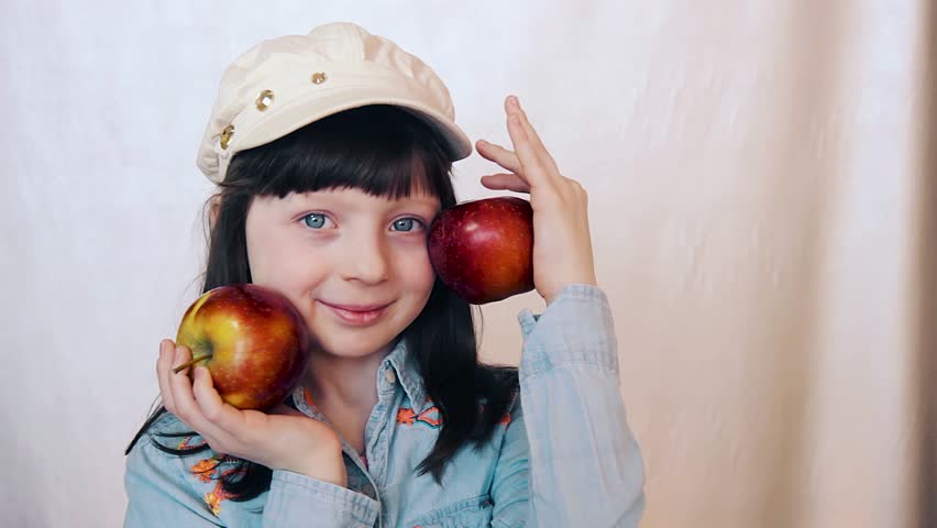girl plays with apple. small girl with blue eyes smiles with appples in hands. apple harvest with a girl for ads
