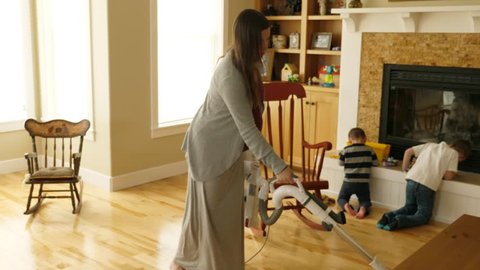 A slow motion shot of a pregnant mother vacuuming and cleaning the house