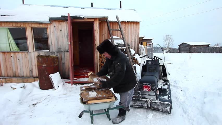 An adult man prepares wood for the winter