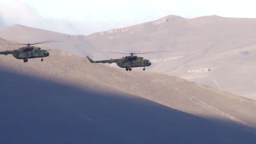 Russian military helicopters fly over a village in the mountains. Concept: aerial reconnaissance, anti-terrorist operation in mountain villages, attack on militants.