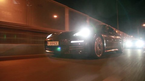 Low angle rolling shot of a Porsche Panamera in traffic at night