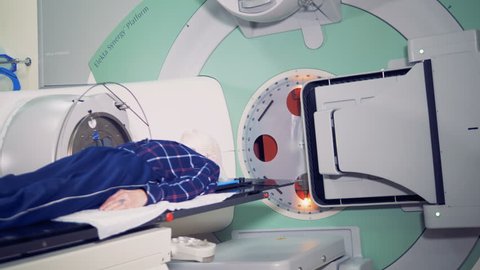 Modern medicine concept. Patient lying on a table while a linear accelerator is treating him