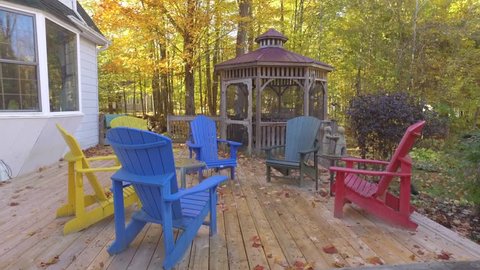 adirondack and muskoka chairs on deck with fall colours 4k gimbal approach real estate