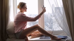 Beautiful woman making selfie on window sill - Powered by Shutterstock - Get 15% off with code: PIKWIZARD15