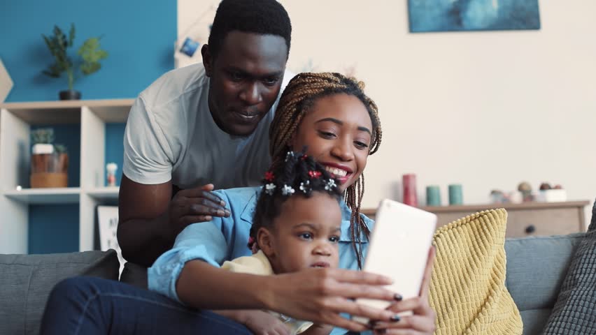 Cheerful African American family takes selfie in their cozy living room. Having fun, social networks, modern culture. Slow motion, close up view Royalty-Free Stock Footage #1008693136