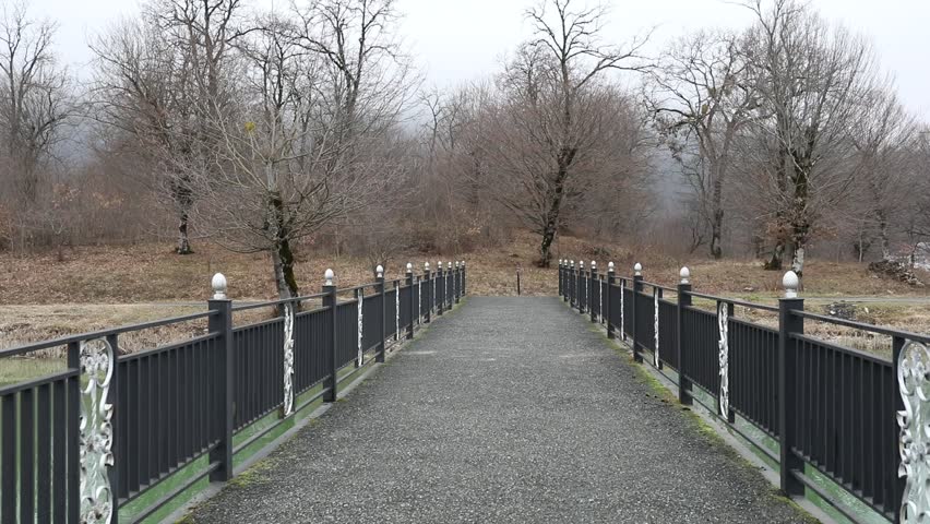 Amazing landscape of bridge reflect on surface water of lake, fog evaporate from pond make romantic scene or Beautiful bridge on lake with trees at fog. Iron bridge over lake in misty morning. Slider 