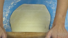 Slow motion footage. Baker hand kneading and flipping dough with rolling pin